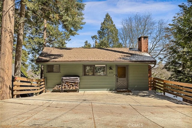 rear view of property with a chimney and fence