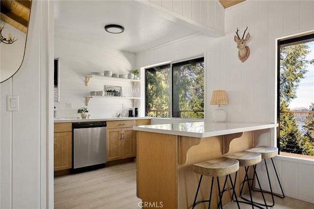 kitchen featuring a kitchen breakfast bar, light countertops, dishwasher, open shelves, and plenty of natural light