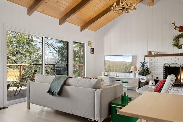 living area with lofted ceiling with beams, a fireplace, wood finished floors, visible vents, and wood ceiling