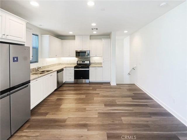 kitchen with stainless steel appliances, wood finished floors, a sink, visible vents, and white cabinets