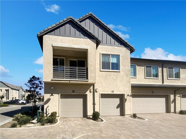 3622 E Delight Paseo Unit 112, Ontario, CA 91761 - view of front facade featuring board and batten siding, a garage, a balcony, and stucco siding