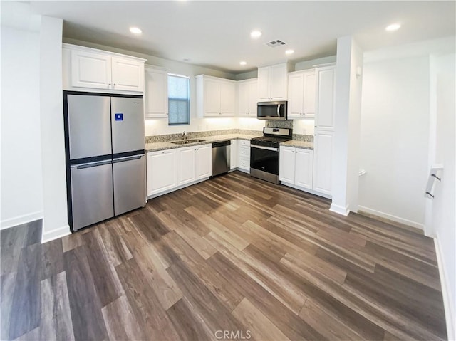 kitchen featuring light stone countertops, white cabinetry, appliances with stainless steel finishes, and a sink