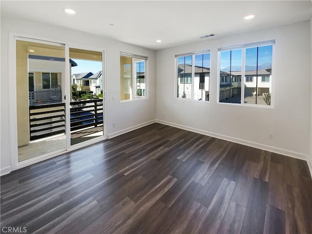 unfurnished room with dark wood-type flooring, recessed lighting, visible vents, and baseboards