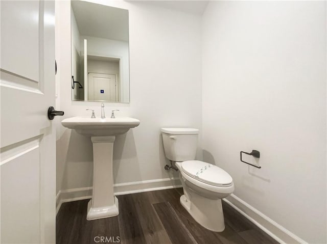 bathroom with a sink, wood finished floors, toilet, and baseboards