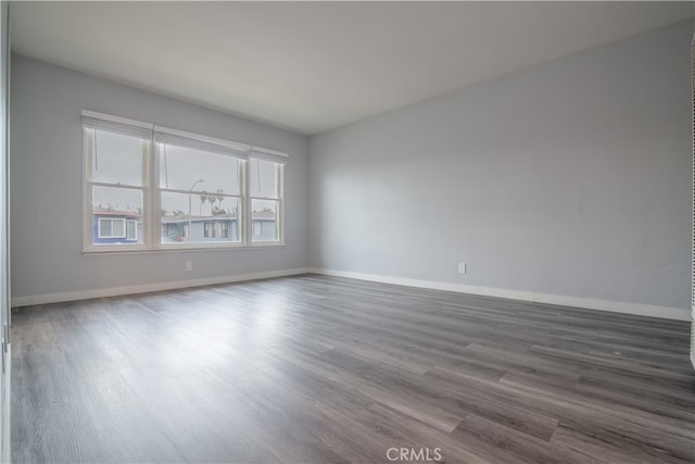 spare room featuring dark wood-type flooring and baseboards