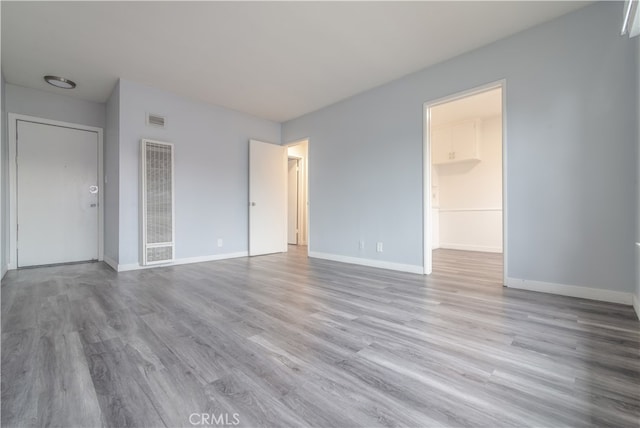 unfurnished bedroom featuring a closet, visible vents, baseboards, and wood finished floors