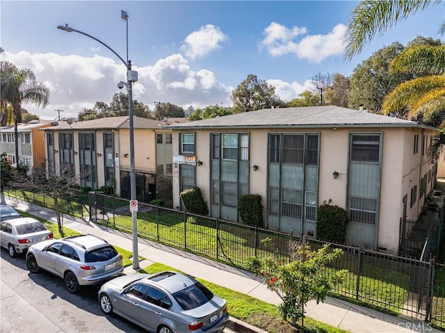 view of building exterior featuring a fenced front yard and a residential view