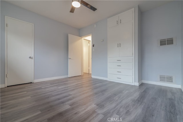 unfurnished bedroom with visible vents, baseboards, and wood finished floors