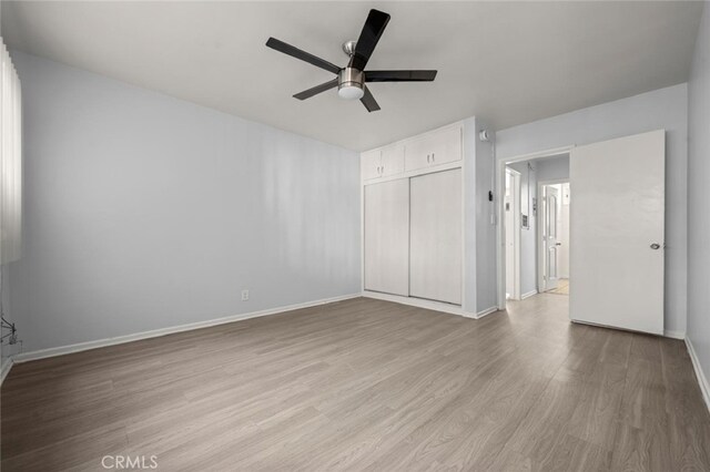 unfurnished bedroom with a ceiling fan, light wood-type flooring, a closet, and baseboards