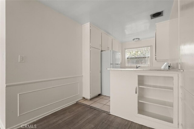 kitchen featuring visible vents, white cabinetry, light wood-style floors, light countertops, and freestanding refrigerator