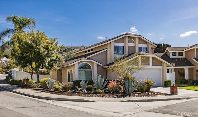 view of front of property featuring a garage, concrete driveway, fence, and stucco siding