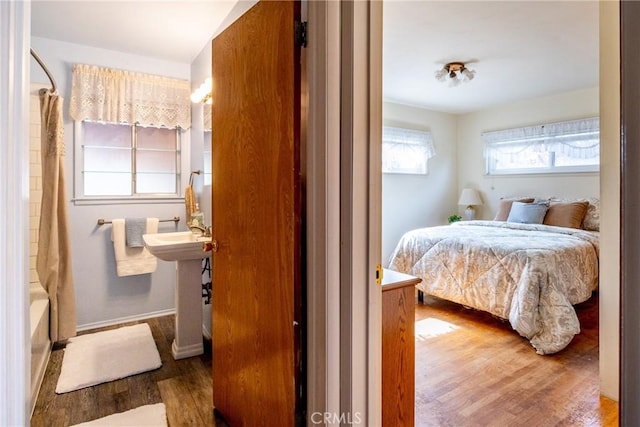 bedroom featuring a sink, baseboards, and wood finished floors