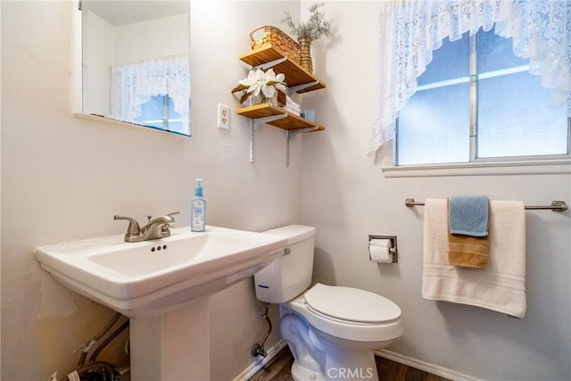 half bathroom featuring toilet, baseboards, a sink, and wood finished floors