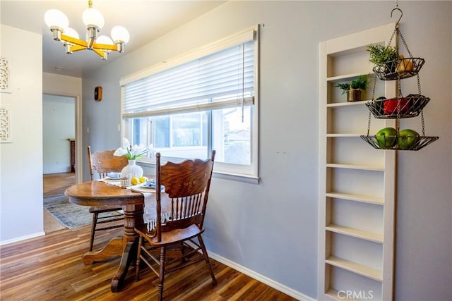 dining area with a notable chandelier, built in shelves, baseboards, and wood finished floors