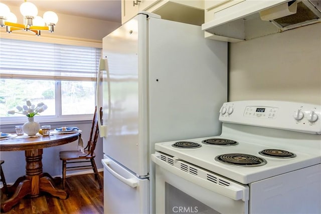 kitchen featuring white appliances, under cabinet range hood, dark wood-type flooring, and an inviting chandelier