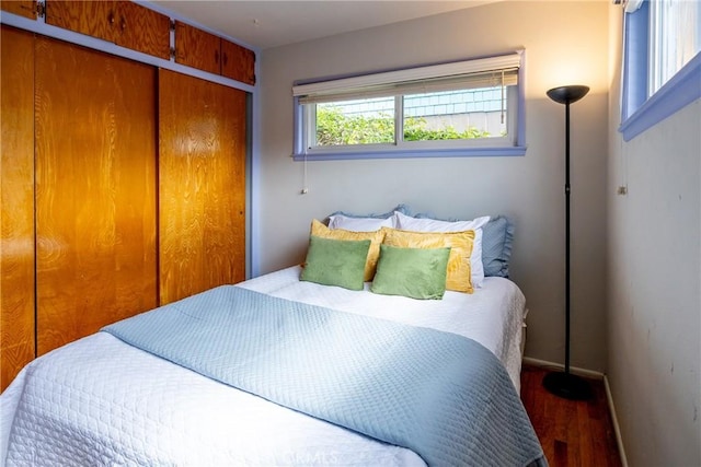 bedroom with a closet, baseboards, and wood finished floors