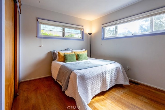 bedroom featuring visible vents, baseboards, and wood finished floors