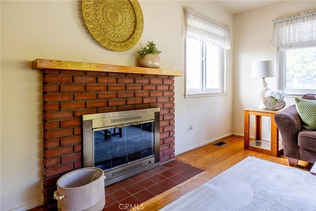 interior space featuring baseboards, a fireplace, visible vents, and wood finished floors