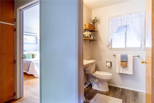 ensuite bathroom featuring baseboards, ensuite bathroom, toilet, and wood finished floors