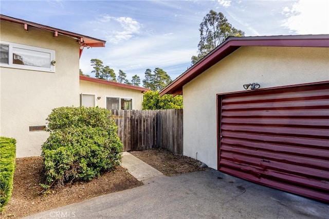 view of side of property with fence and stucco siding