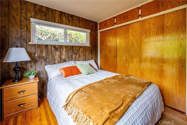 bedroom featuring a closet, wood walls, and wood finished floors