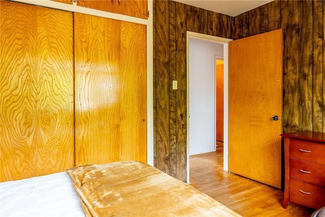 bedroom with wooden walls, a closet, and wood finished floors