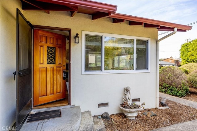 doorway to property featuring crawl space, visible vents, and stucco siding