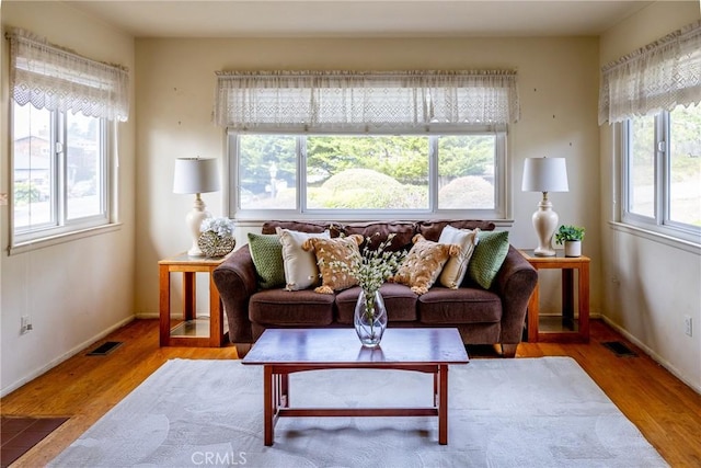 living area featuring plenty of natural light, visible vents, and wood finished floors