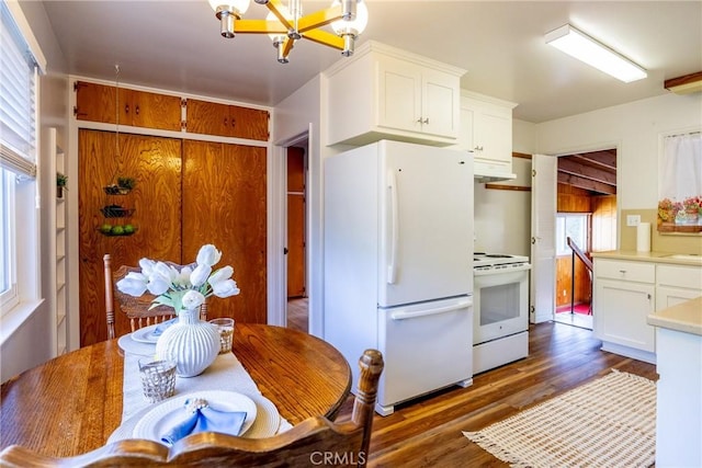 kitchen featuring a chandelier, under cabinet range hood, white appliances, dark wood-type flooring, and white cabinetry