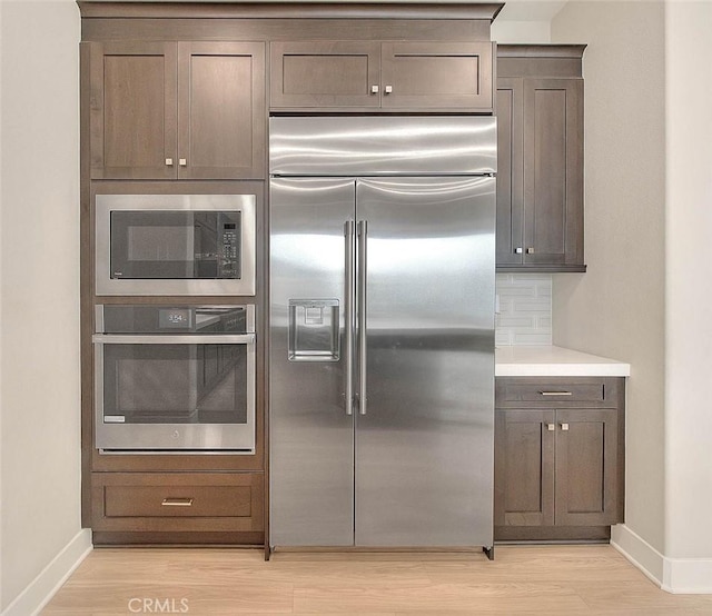 114 Source, Irvine, CA 92618 - kitchen featuring built in appliances, light wood-style floors, light countertops, and decorative backsplash