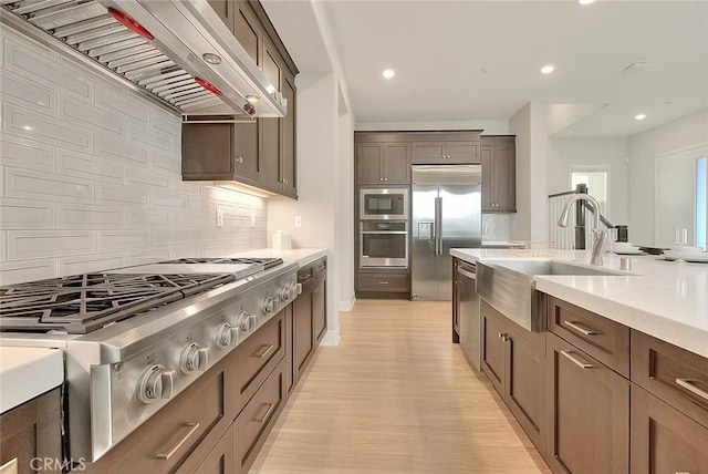 114 Source, Irvine, CA 92618 - kitchen with built in appliances, range hood, a sink, light countertops, and backsplash