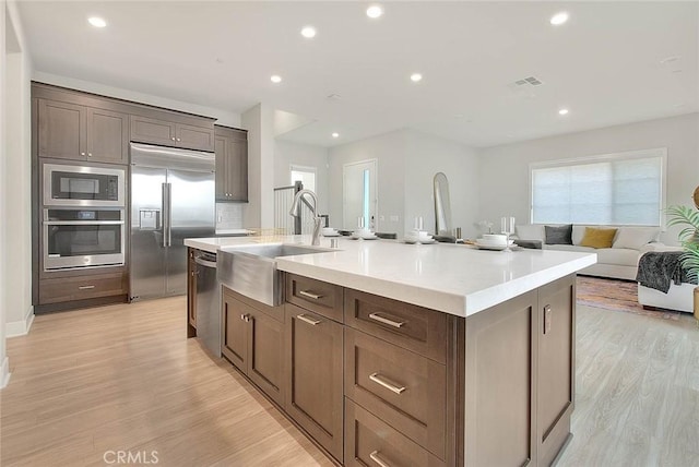 114 Source, Irvine, CA 92618 - kitchen with built in appliances, a sink, an island with sink, light wood-style floors, and recessed lighting