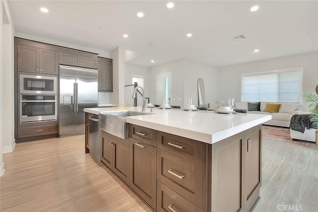 114 Source, Irvine, CA 92618 - kitchen with built in appliances, an island with sink, light wood finished floors, light countertops, and recessed lighting
