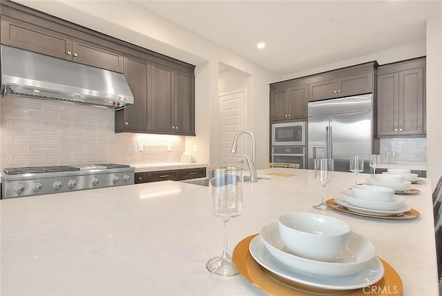 114 Source, Irvine, CA 92618 - kitchen featuring built in appliances, under cabinet range hood, tasteful backsplash, dark brown cabinets, and recessed lighting