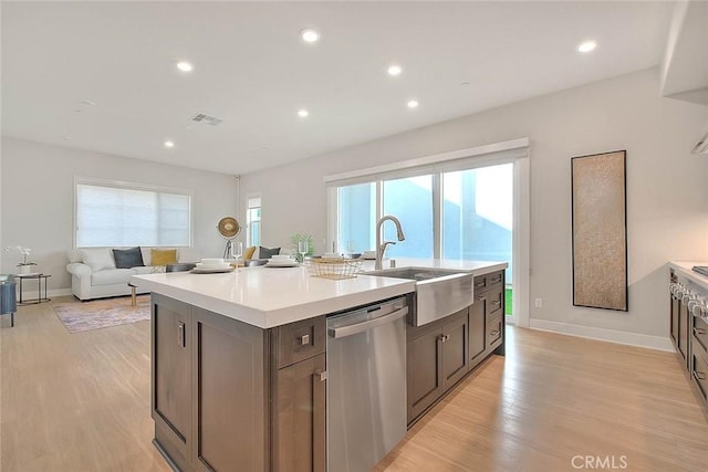114 Source, Irvine, CA 92618 - kitchen featuring stainless steel dishwasher, a sink, a kitchen island with sink, light countertops, and light wood-style floors