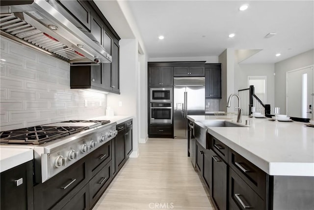 114 Source, Irvine, CA 92618 - kitchen featuring built in appliances, wall chimney exhaust hood, a sink, light countertops, and recessed lighting