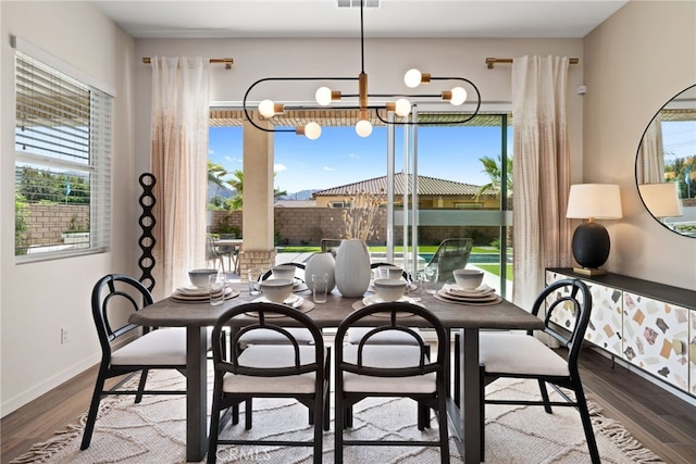 dining area with baseboards, visible vents, an inviting chandelier, and wood finished floors