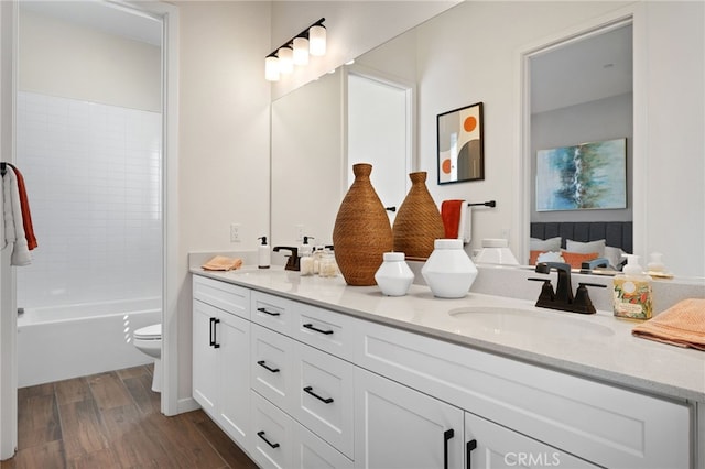 bathroom with double vanity, wood finished floors, a sink, and toilet