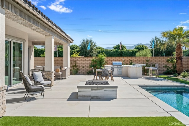 view of pool with a patio area, an outdoor fire pit, an outdoor kitchen, and fence