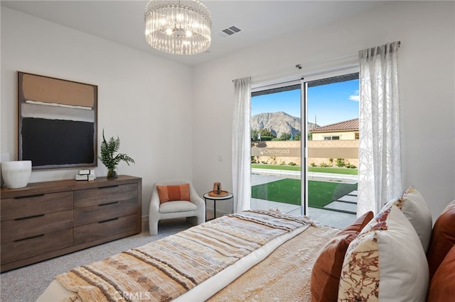 carpeted bedroom with a mountain view, access to outside, visible vents, and an inviting chandelier