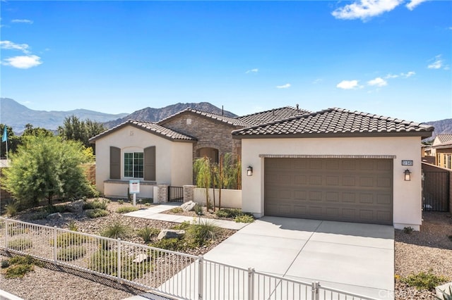 mediterranean / spanish home featuring driveway, a fenced front yard, a mountain view, and stucco siding