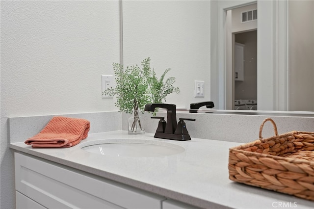 bathroom featuring a textured wall, visible vents, and vanity