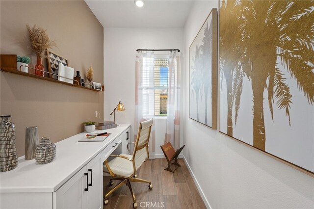 office area featuring light wood-style floors, baseboards, built in desk, and recessed lighting