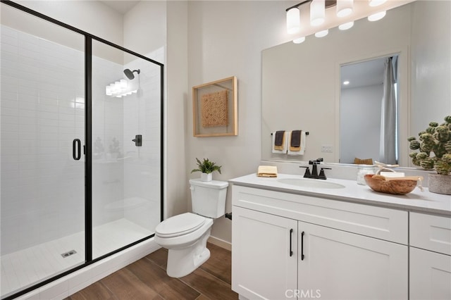 bathroom featuring a stall shower, vanity, toilet, and wood finished floors