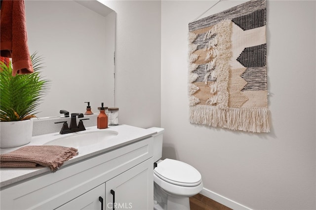 bathroom featuring toilet, wood finished floors, vanity, and baseboards