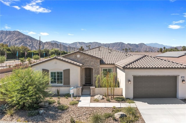 mediterranean / spanish home featuring a tiled roof, concrete driveway, a mountain view, and stucco siding