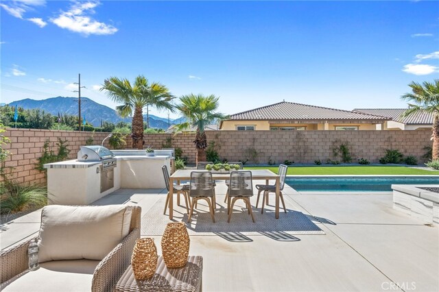 view of patio / terrace with a fenced backyard, a mountain view, and area for grilling