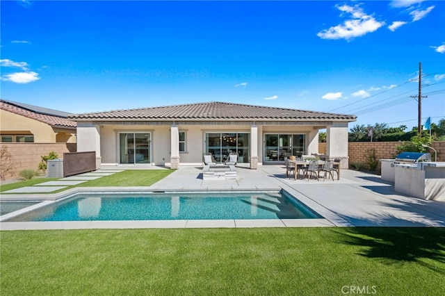 back of house featuring a patio area, a fenced backyard, an outdoor kitchen, and a yard