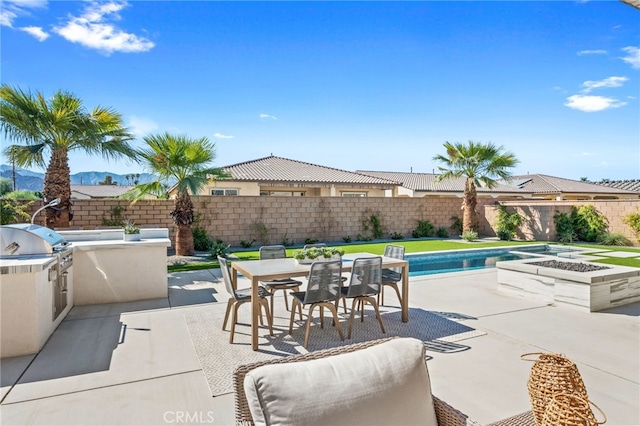 view of patio with exterior kitchen, grilling area, outdoor dining space, and a fenced backyard