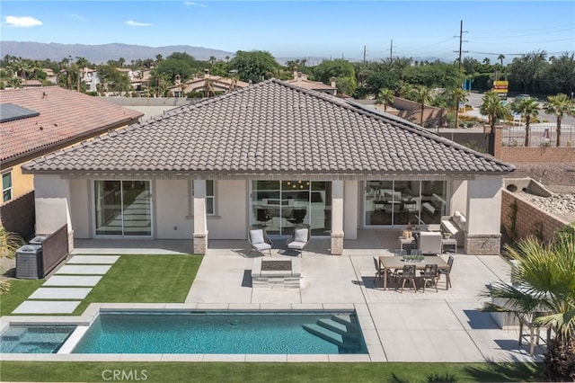 rear view of property featuring a fenced in pool, stucco siding, a patio area, fence, and a tiled roof